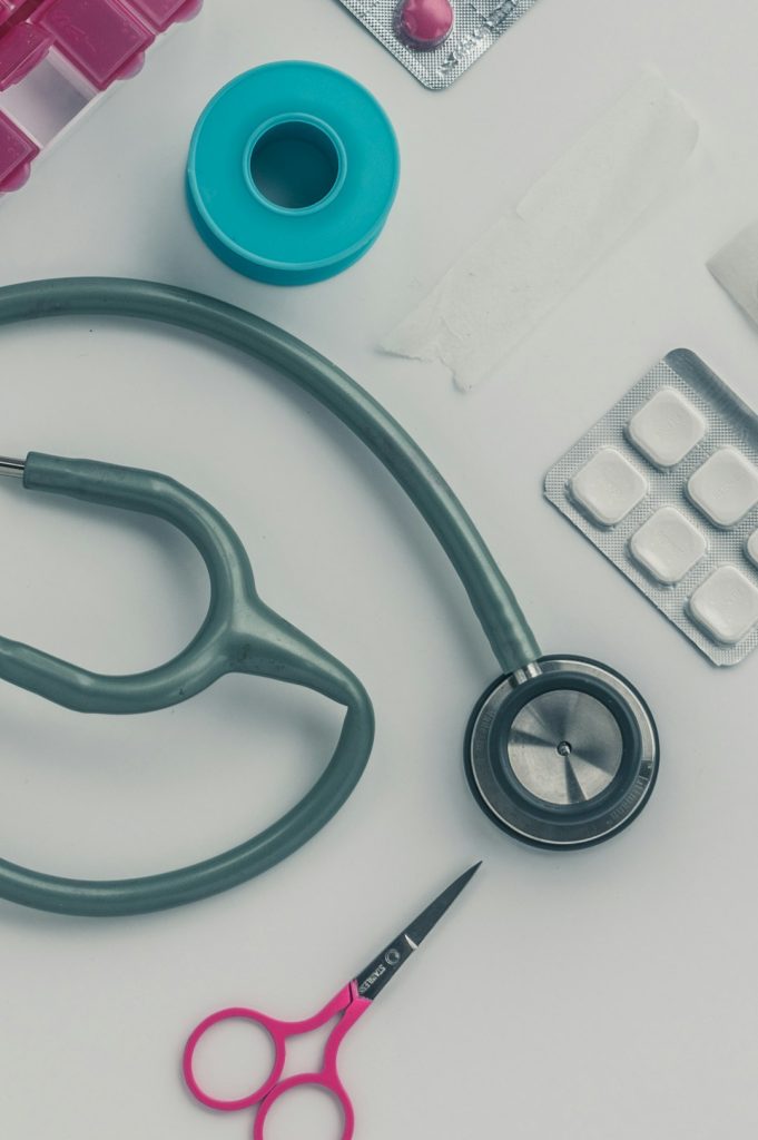 Doctors attributes - Stethoscope, scissors and pills on a table.